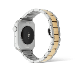 Back view of an Apple Watch with the Daniel Wellington Smartwatch Iconic Link two-tone strap, featuring a three-link design with brushed silver outer links and a polished gold center link.